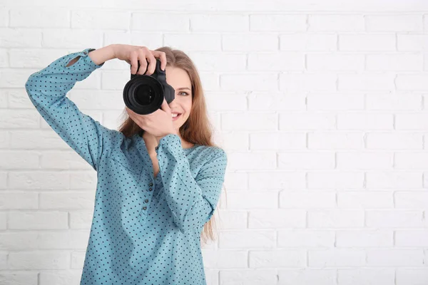 Fotógrafo femenino con cámara sobre fondo de ladrillo — Foto de Stock