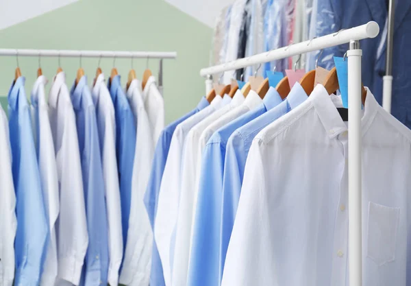 Стойки с чистой одеждой на вешалках после химчистки в помещении — стоковое фото