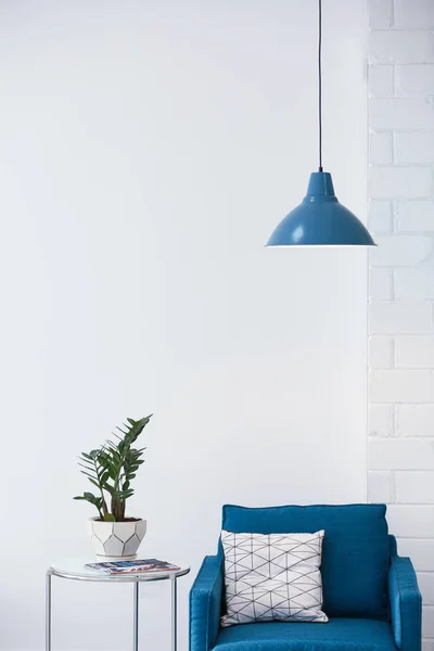 Modern lamp with plant on table and armchair indoors