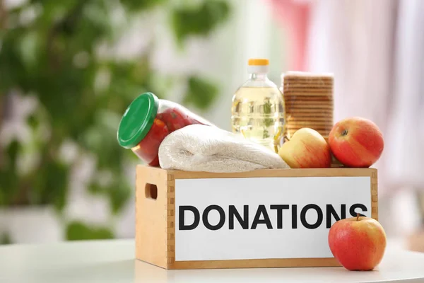 Caja de donaciones con productos alimenticios en la mesa en interiores —  Fotos de Stock