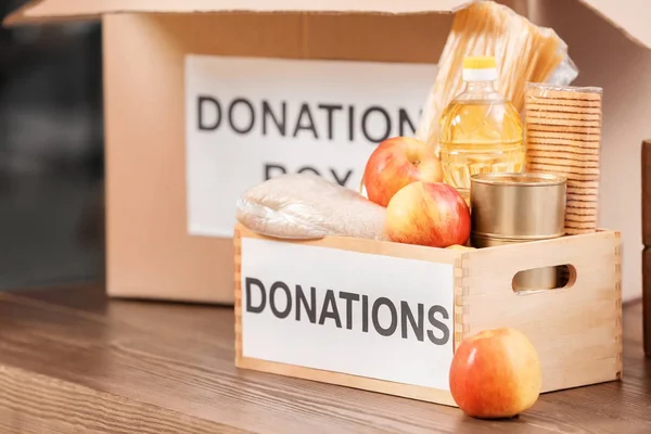 Caja de donación con productos en la mesa en el interior —  Fotos de Stock