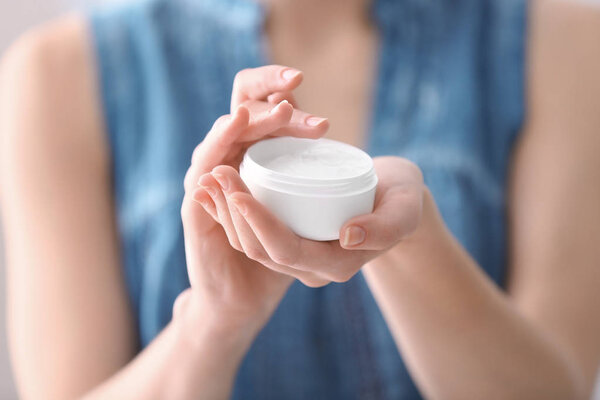 Young woman holding jar with hand cream, closeup