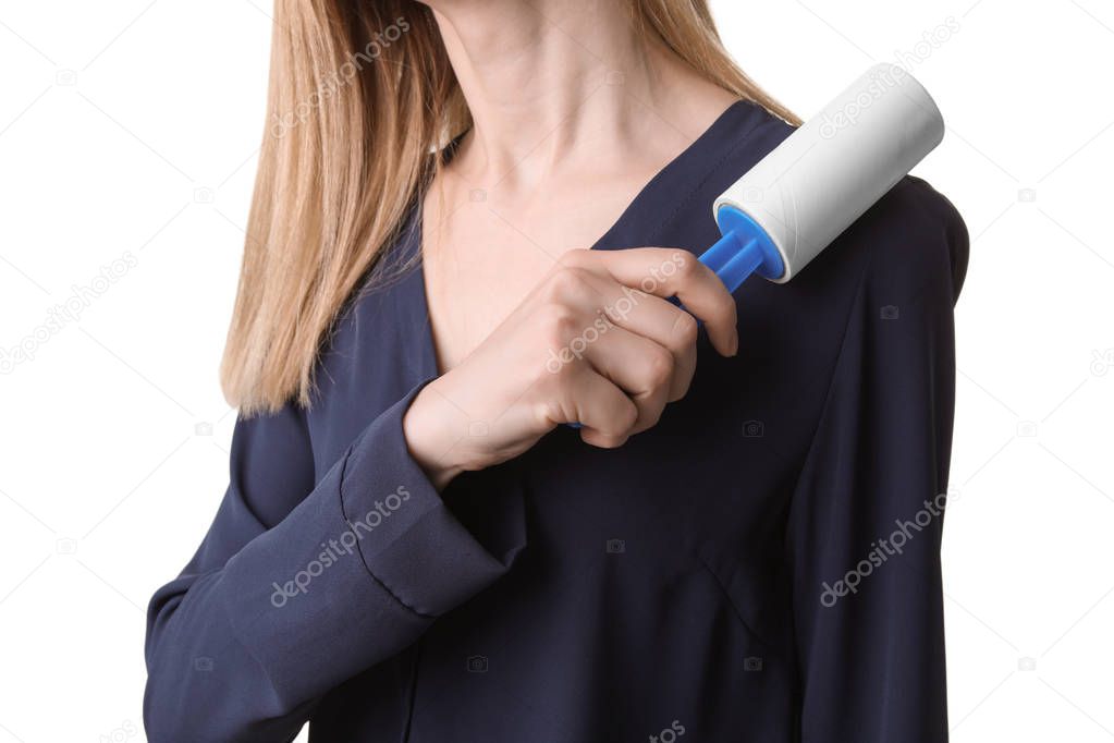 Young woman cleaning blouse with lint roller on white background