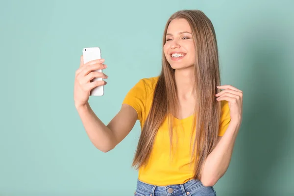 Junge schöne Frau macht Selfie vor farbigem Hintergrund — Stockfoto