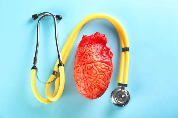 Estetoscopio y modelo de corazón sobre fondo de color. Concepto de ataque cardíaco — Foto de Stock