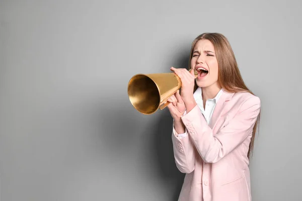 Jonge vrouw schreeuwen in Megafoon op grijze achtergrond — Stockfoto