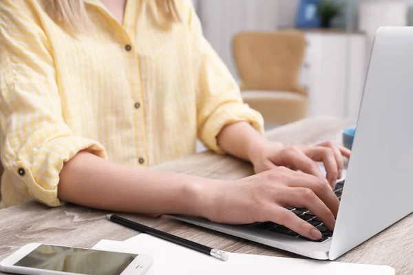 Jovem mulher trabalhando com laptop na mesa no escritório em casa, close-up — Fotografia de Stock