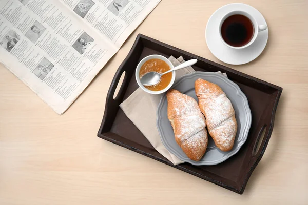 Colazione gustosa con croissant freschi, marmellata e tazza di tè in tavola — Foto Stock