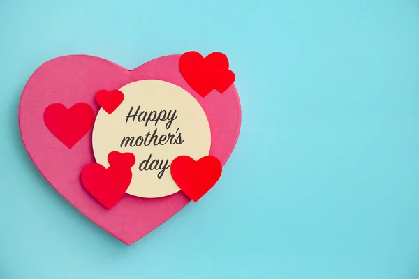 Surprise for Mother's Day with greeting card and paper hearts on color background — Stock Photo, Image