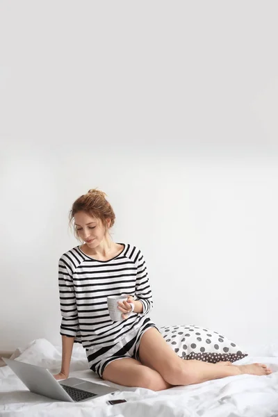 Női blogger-val laptop és csésze kávé ágyon — Stock Fotó