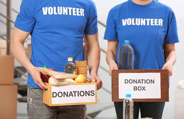 Frivilliga holding donation lådor med livsmedelsprodukter inomhus Stockbild