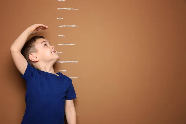 Маленький мальчик измеряет свой рост на цветном фоне — стоковое фото
