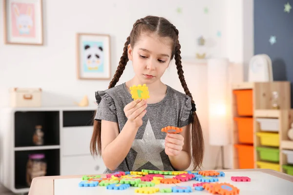 Lite autistisk flicka som leker med pussel hemma — Stockfoto