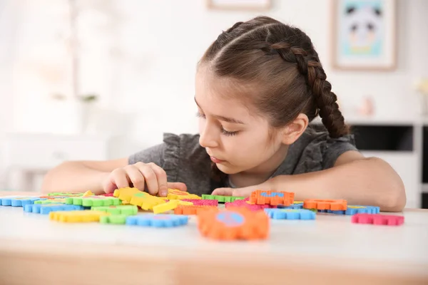 Маленькая аутистка, играющая с головоломками дома — стоковое фото