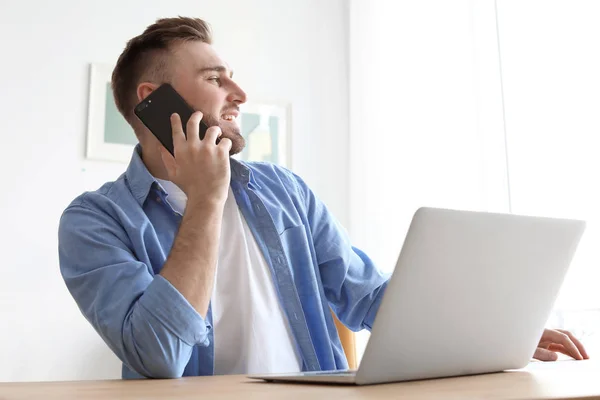 Jonge man praten op mobiele telefoon tijdens het werken met de laptop op Bureau. Kantoor aan huis — Stockfoto