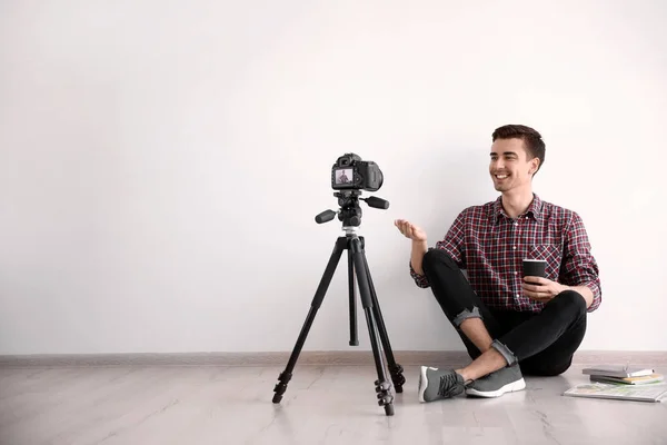 Молодий блогер записує відео біля світлої стіни — стокове фото