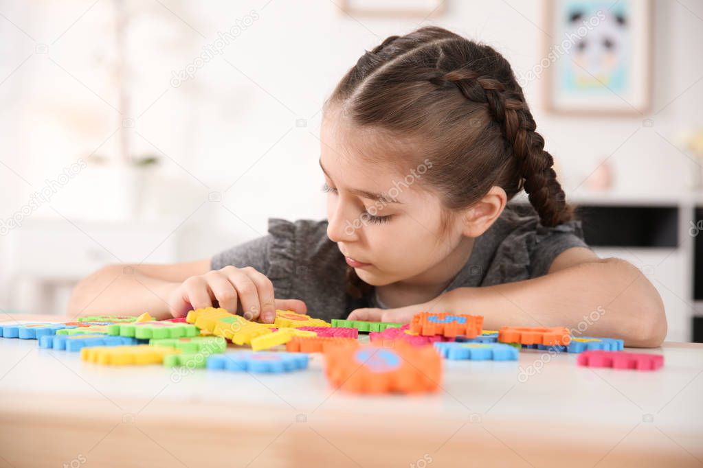 Little autistic girl playing with puzzles at home