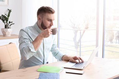 Laptop ile masa başında çalışırken içme kahve genç adam. Ev ofis