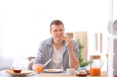 Genç adam lezzetli yemek masasında reçelli ekmek tost