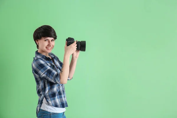Young female photographer with camera on color background — Stock Photo, Image