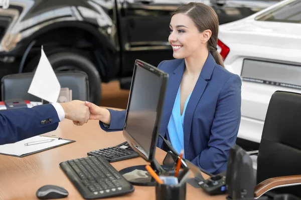 若い女性の車サロンでセールスマンと握手 — ストック写真