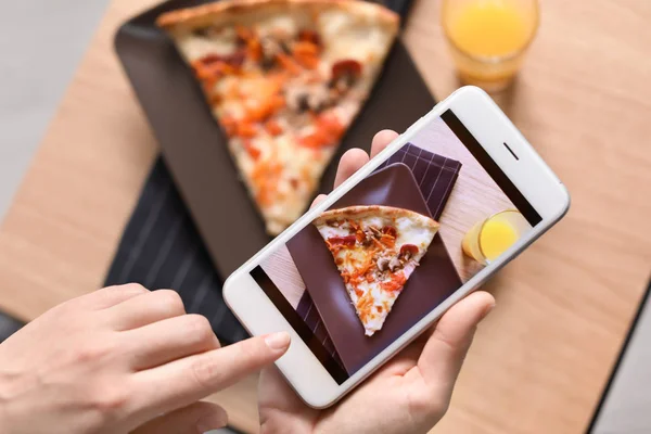 Food blogger photographing piece of pizza with mobile phone, closeup