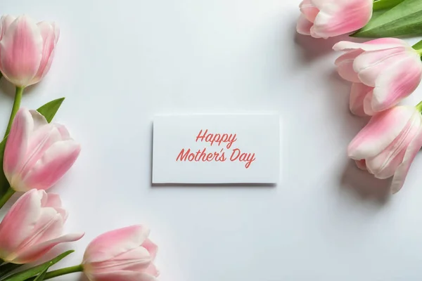 Beautiful tulips and greeting card with words "Happy Mother's Day" on light background, top view — Stock Photo, Image