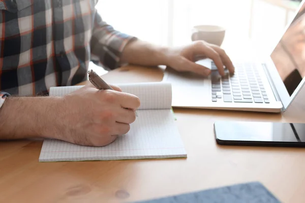 若い男は、デスクでノート パソコンでの作業します。ホーム オフィス — ストック写真