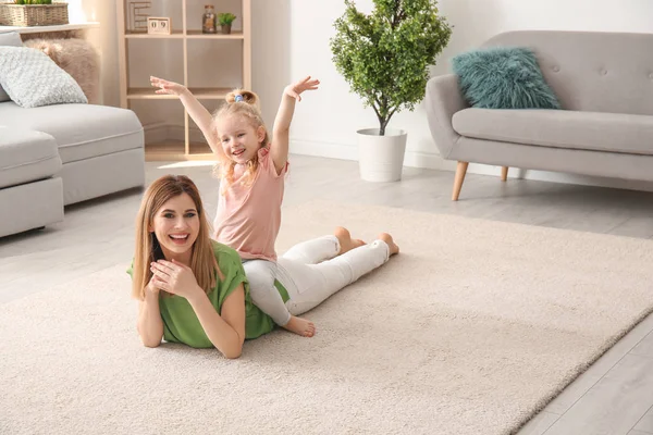 Nettes kleines Mädchen und ihre Mutter auf kuscheligem Teppich zu Hause — Stockfoto