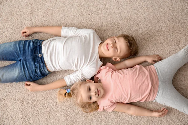 Leuke lieve kinderen liggen op gezellige tapijt thuis, top uitzicht — Stockfoto