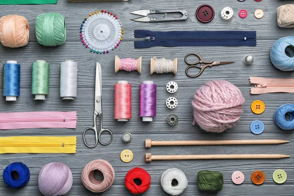 Flat lay composition with sewing threads and accessories on wooden background