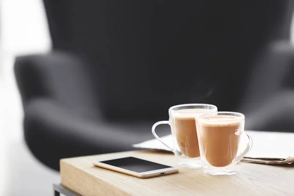 Tazas de café y teléfono móvil en la mesa — Foto de Stock