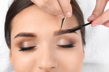 Güzellik salonunda profesyonel kaş düzeltme prosedürü olan genç bir kadın.