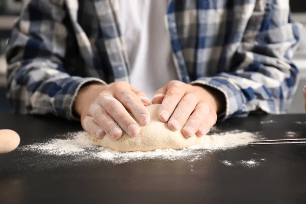 Człowiek, wyrabiania ciasta na stół przykryty mąki w kuchni — Zdjęcie stockowe