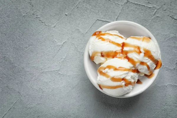 Gustoso gelato con salsa al caramello in ciotola sul tavolo — Foto Stock