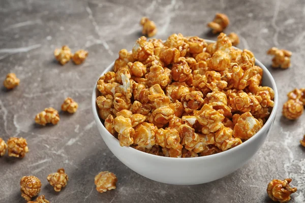 Delicious popcorn with caramel in bowl on table