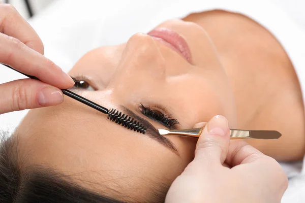 Jonge vrouw met professionele wenkbrauw correctie procedure in schoonheidssalon — Stockfoto