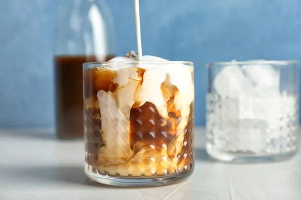 Verser le lait dans le verre avec café infusé froid sur la table — Photo