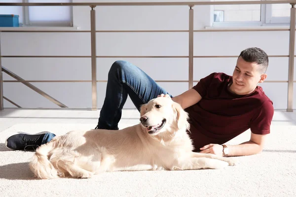 自宅のカーペットの上に横たわっている犬を持つハンサムな男 — ストック写真