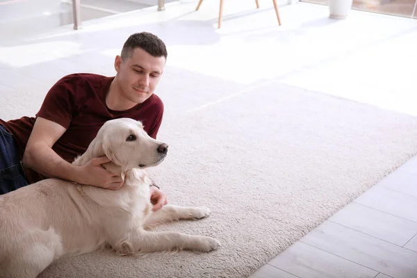 Evde halı üzerinde yalan köpekli yakışıklı adam