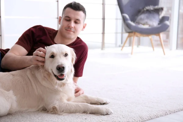Красивый мужчина с собакой лежит дома на ковре — стоковое фото