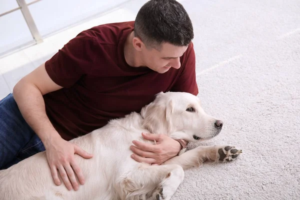 Bonito homem com cão deitado no tapete em casa — Fotografia de Stock