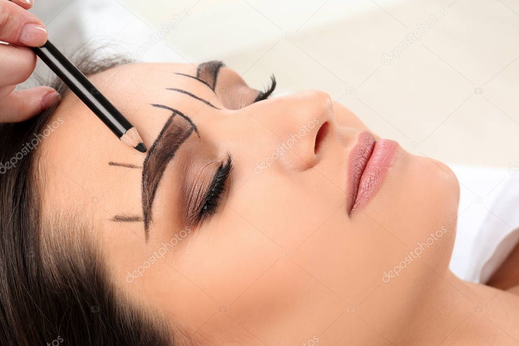 Cosmetologist preparing young woman for  eyebrow permanent makeup procedure, closeup