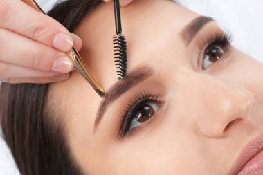 Güzellik salonunda profesyonel kaş düzeltme prosedürü olan genç bir kadın.