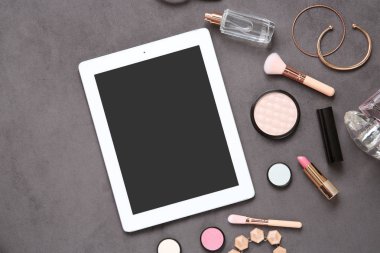 Gri arka plan üzerinde kadın için tablet ve makyaj ürünleri ile düz yatıyordu kompozisyon