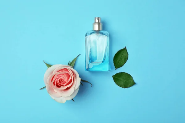 Botol parfum dan mawar di latar belakang warna, tampilan atas — Stok Foto