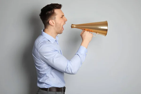 A fiatalember kiabálás a megafon, világos háttér — Stock Fotó