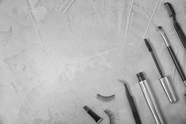 Composição plana com pestanas falsas e ferramentas cosméticas em fundo cinza — Fotografia de Stock