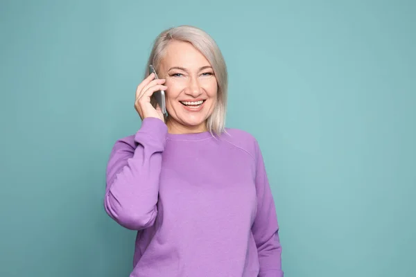 Mujer madura hablando en el teléfono móvil contra el fondo de color —  Fotos de Stock