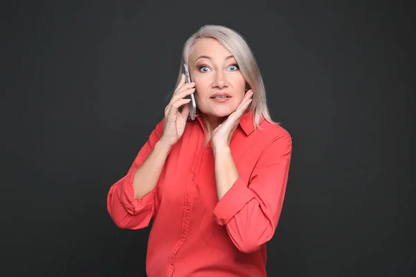 Reife Frau telefoniert vor schwarzem Hintergrund — Stockfoto